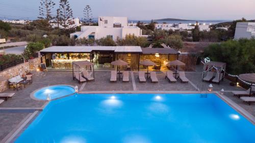 a pool with chairs and a restaurant in the background at Parosland Hotel in Aliki