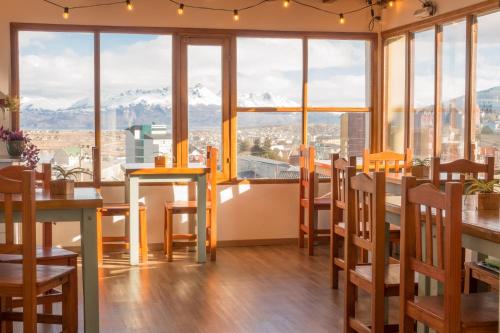 a restaurant with tables and chairs and a view of mountains at Hostería Aonikenk in Ushuaia