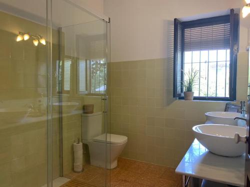 a bathroom with a toilet and two sinks and a shower at Casería San José in Baeza