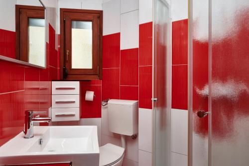 Baño rojo con lavabo y aseo en Holiday House Emma, en Burići