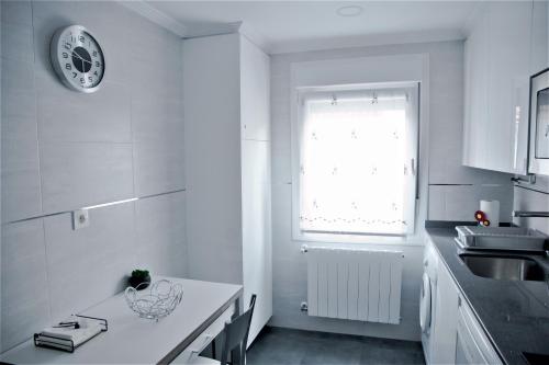 uma cozinha branca com um lavatório e uma janela em Zubia Home Portugalete - Impecable- 3 min metro Bilbao em Portugalete