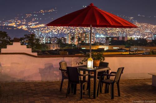 a table with chairs and a red umbrella on a roof at 61Prado Hotel in Medellín