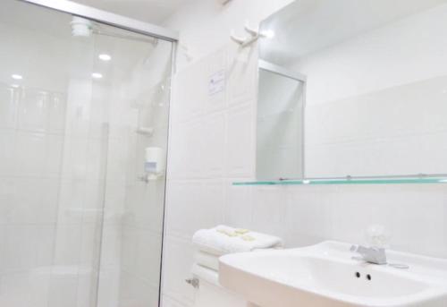 a white bathroom with a sink and a shower at Hotel Thama in Palmira