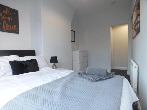 een slaapkamer met een groot wit bed met een deken erop bij Stamford Place by SG Property Group in Crewe