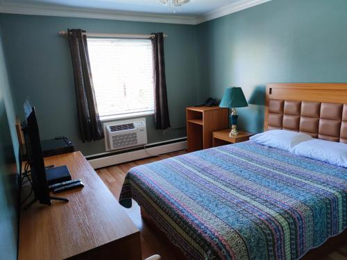 Schlafzimmer mit einem Bett, einem Schreibtisch und einem Fenster in der Unterkunft Pemberton Hotel (Motel) in Pemberton