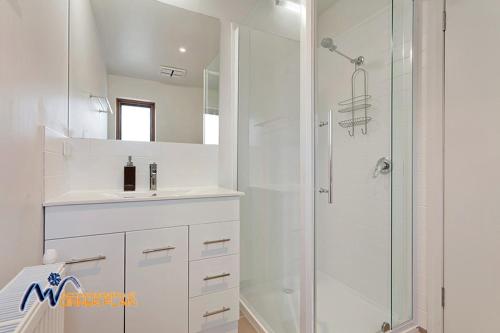 a white bathroom with a shower and a sink at Zoncolan in Dinner Plain