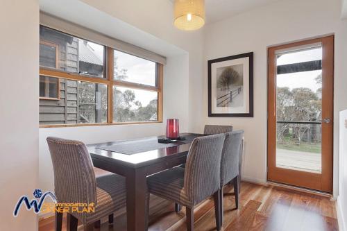 a dining room with a table and chairs and windows at Zoncolan in Dinner Plain