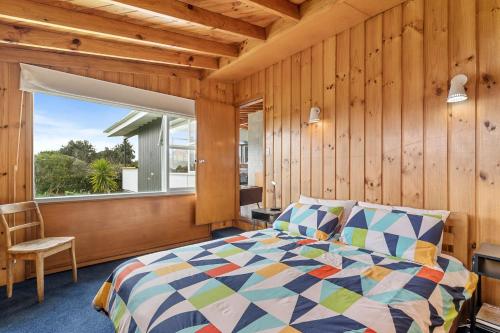 een slaapkamer met een bed en een groot raam bij Queenie - Waikanae Beach Holiday Home in Waikanae
