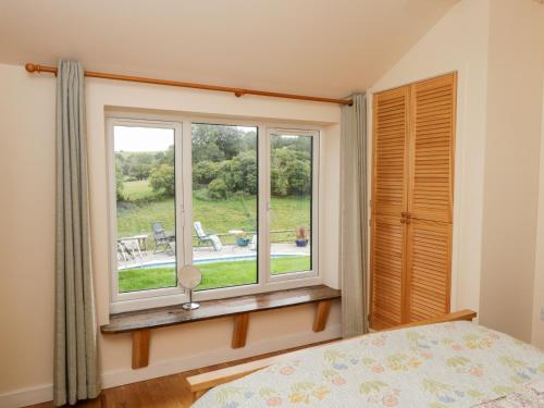 a bedroom with a window with a view of a yard at The Hideout in Ross on Wye