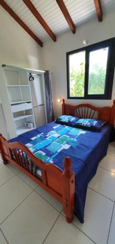 a bedroom with a bed with a blue comforter at Les cottages de roseau in Capesterre-Belle-Eau