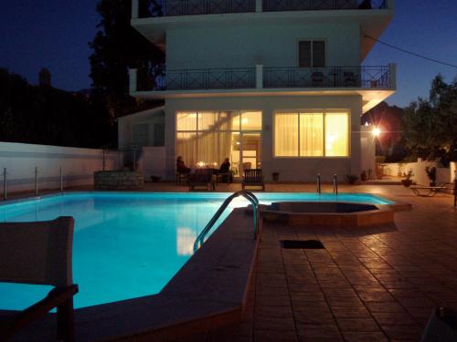 a swimming pool in front of a house at night at Astir Hotel in Karlovasi
