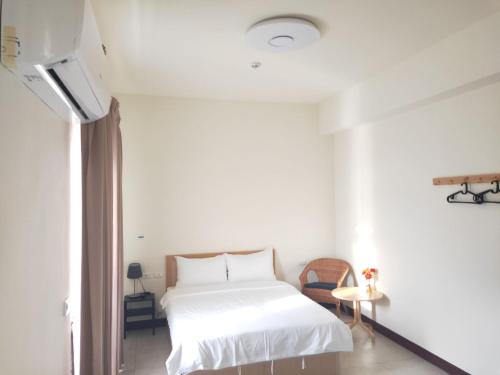a white bedroom with a bed and a tv at 響樂池上電梯民宿1663 Chishang Music Guesthouse in Chishang