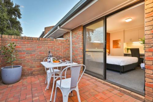 a patio with a white table and chairs on a brick wall at Mildura City Gate Motel in Mildura