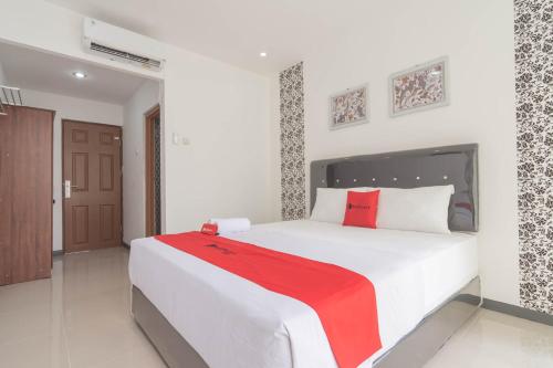 1 dormitorio con 1 cama blanca grande con manta roja en KoolKost @ Regol Park (Minimum Stay 3 Nights), en Bandung
