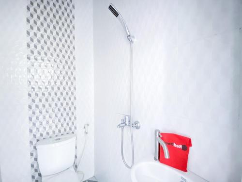 a bathroom with a shower with a toilet and a sink at RedDoorz At Simpang Borobudur in Blimbing
