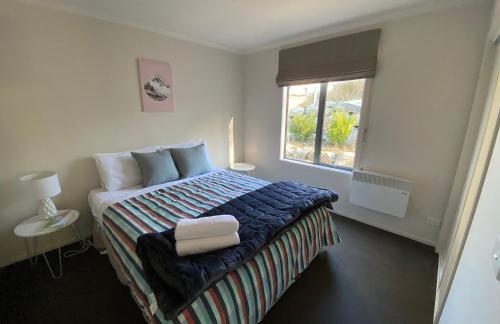 a bedroom with a large bed with a window at Ribbonwood Cottage in Lake Tekapo