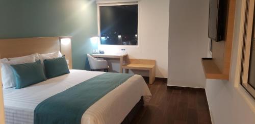a bedroom with a bed and a desk and a window at Hotel Plaza Sol Veracruz in Veracruz