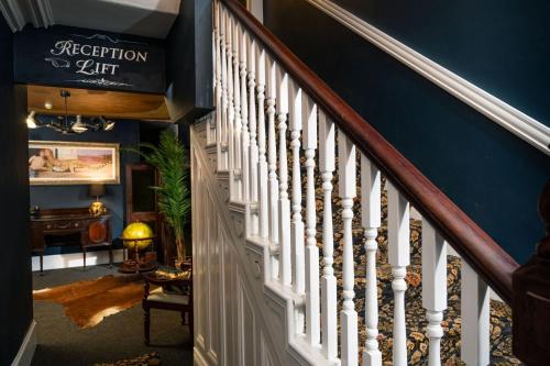 a staircase with white railings and a blue wall at The Harrison Chambers of Distinction in Belfast