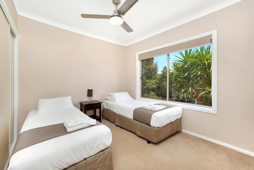 two beds in a room with a window at Kennedy Holiday Villas in Mulwala