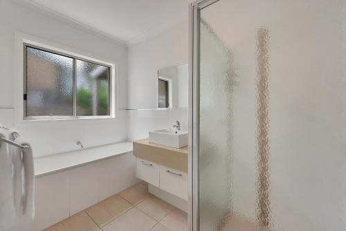 a bathroom with a glass shower and a sink at Kennedy Holiday Villas in Mulwala