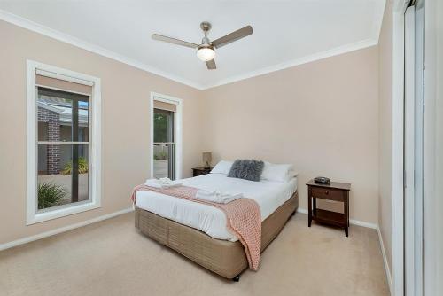 a white bedroom with a bed and a window at Kennedy Holiday Villas in Mulwala