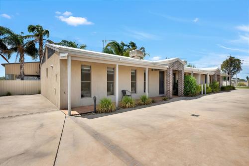 a row of houses with palm trees and a driveway at Kennedy Holiday Villas in Mulwala