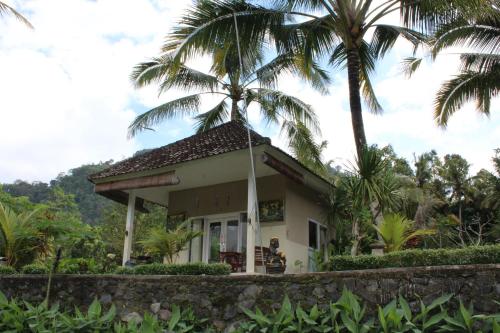 una casa con palmeras en el fondo en Pondok Tepi Sungai, en Sidemen