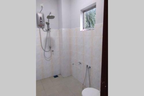 a bathroom with a shower with a toilet and a window at Meru Homestay suitable for up to 7 people in Klang