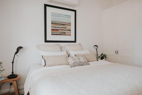 ein weißes Schlafzimmer mit einem weißen Bett und Kissen in der Unterkunft Apartments on Belmore - The Ledger in Yarrawonga