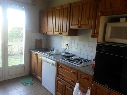 eine Küche mit Holzschränken und einem Herd mit Backofen in der Unterkunft Les Avocettes in Piriac-sur-Mer