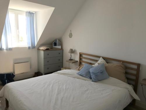 ein Schlafzimmer mit einem weißen Bett mit blauen Kissen in der Unterkunft Les Avocettes in Piriac-sur-Mer