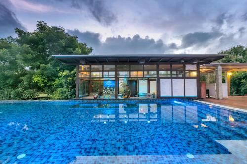 a swimming pool in front of a villa at Club Mahindra Puducherry in Pūrnānkuppam