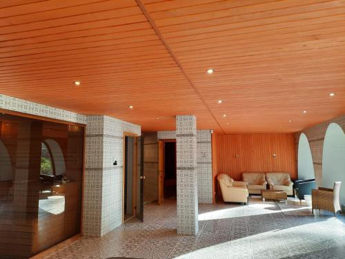 a living room with a wooden ceiling and a couch at Meždzirnas Country House & SPA in Kabile