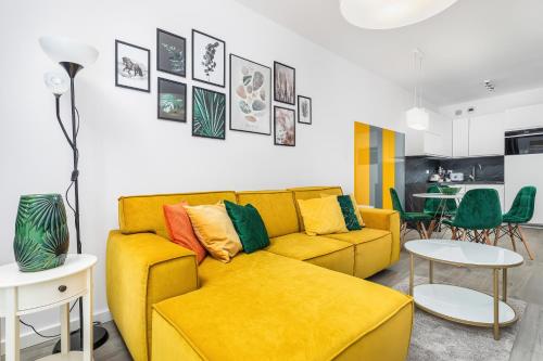 a yellow couch with colorful pillows in a living room at Jantar Apartamenty - Nadmorskie Tarasy SPA 2 in Kołobrzeg