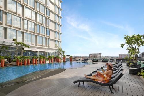 a woman sitting in a chair next to a swimming pool at Ibis Samarinda in Samarinda