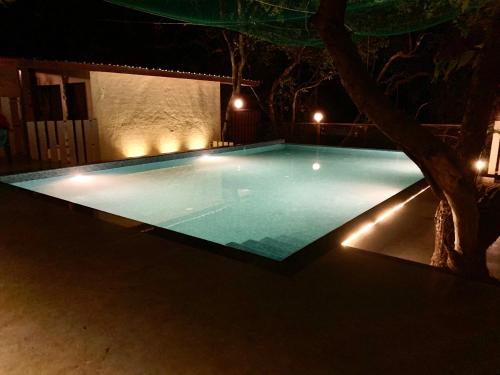 an empty swimming pool at night with lights at Honeywood Holiday Homes in Mahabaleshwar