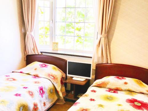 a bedroom with two beds and a computer monitor and a window at Appi Life is Beautiful in Hachimantai