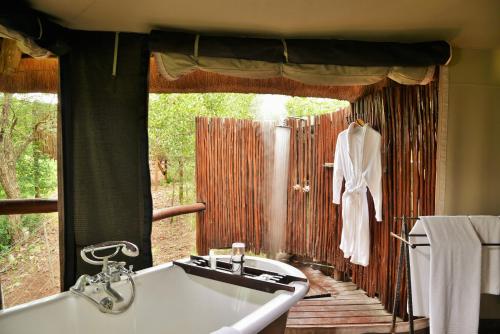 a bathroom with a tub and a sink and a window at Shishangeni by BON Hotels, Kruger National Park in Komatipoort