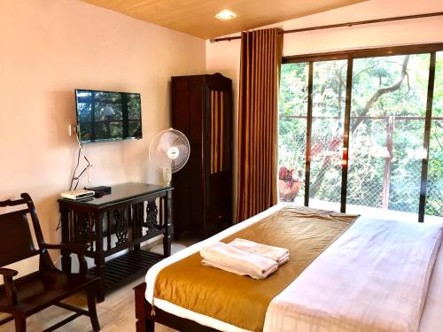 a bedroom with a bed and a desk and a window at Honeywood Holiday Homes in Mahabaleshwar