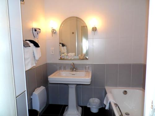 a bathroom with a sink and a mirror at Clos de Vallombreuse, The Originals Relais in Douarnenez