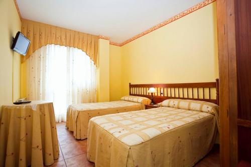 a hotel room with two beds and a window at Hospedería Las Calzadas in San Vicente de la Barquera