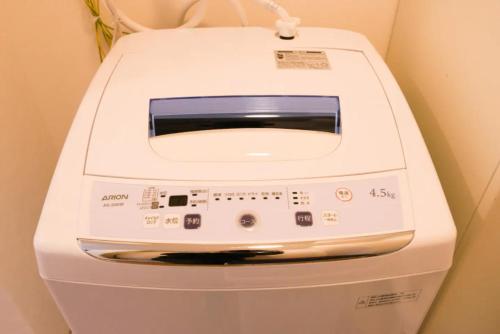 a white washing machine sitting next to a wall at Kyoto Yoshii House in Kyoto