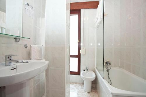a white bathroom with a sink and a toilet at Hospedería Las Calzadas in San Vicente de la Barquera