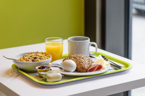 una bandeja de alimentos para el desayuno y un vaso de zumo de naranja en Ibis budget München Airport Erding, en Erding