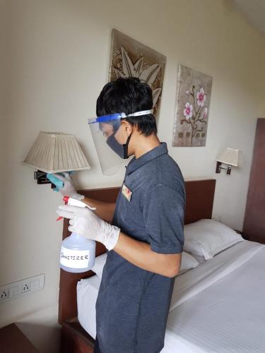 a man holding a hair dryer in a bedroom at The Queeny in Vasco Da Gama