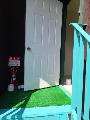 an open white door with a green carpet at Bluebird Hotel in Fujikawaguchiko