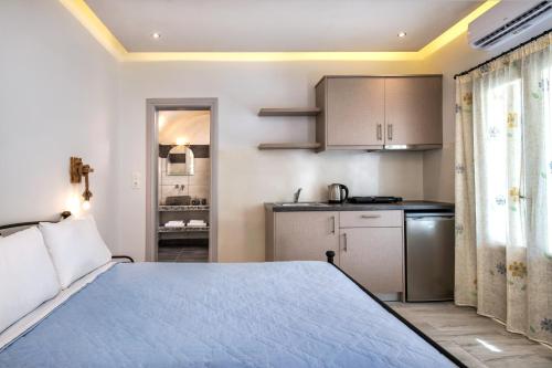 a bedroom with a blue bed and a kitchen at Villa Eleftheria in Perivolos