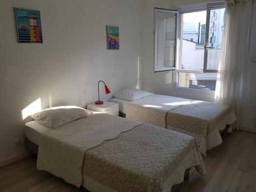 zwei Betten in einem Zimmer mit Fenster in der Unterkunft Cassiopée II Appt Classé 3 étoiles 2 chambres terrasse garage in Les Sables-dʼOlonne