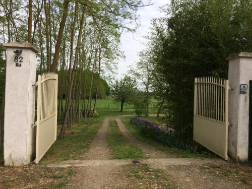 a gate leading to a dirt road with purple flowers at la Sainterie in Savonnières