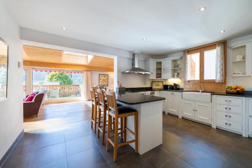 a kitchen with white cabinets and a island with bar stools at Chalet Balthazar in Villars-sur-Ollon